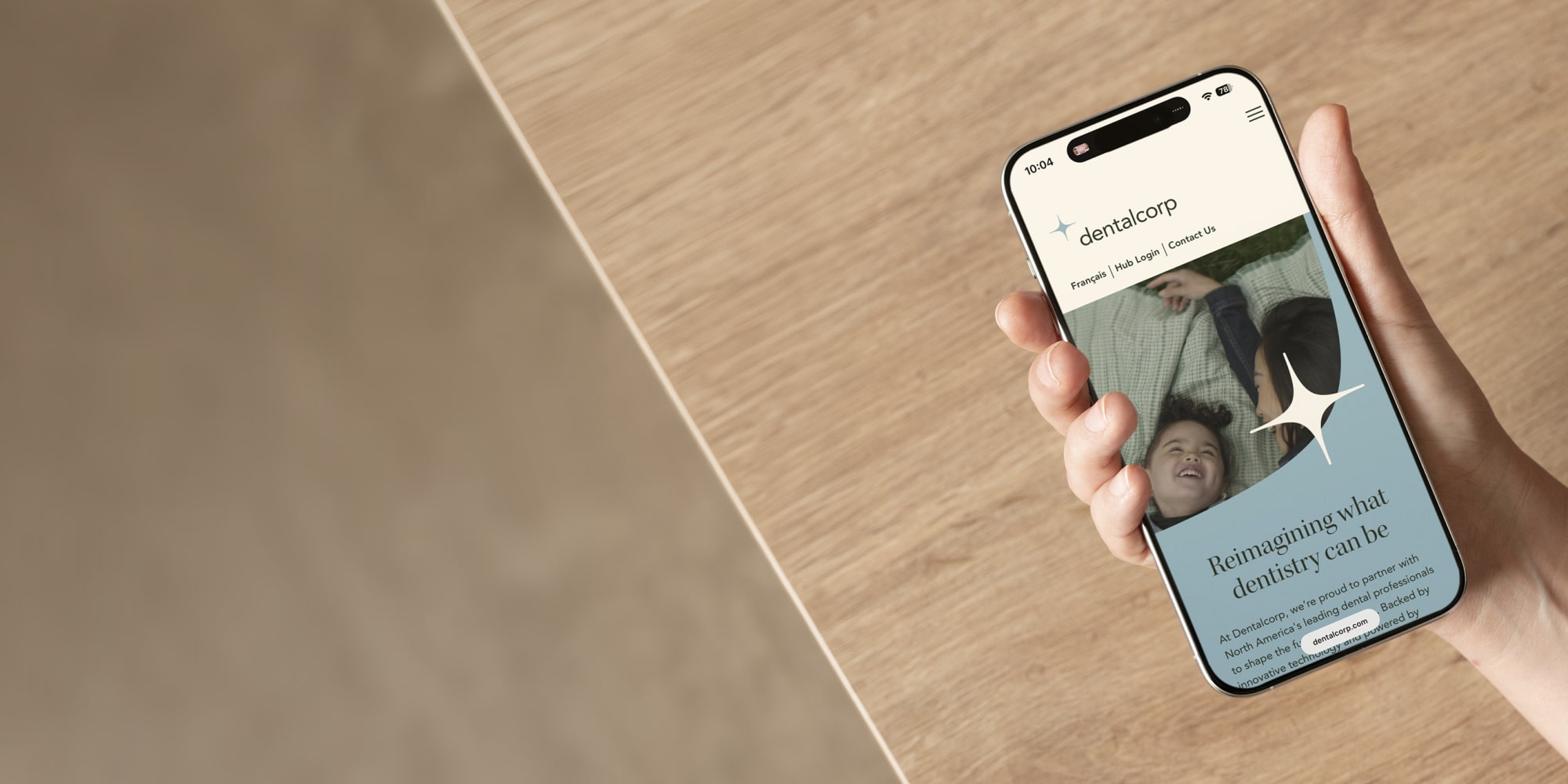 Person holding a cell phone with the dentalcorp corporate website displaying.