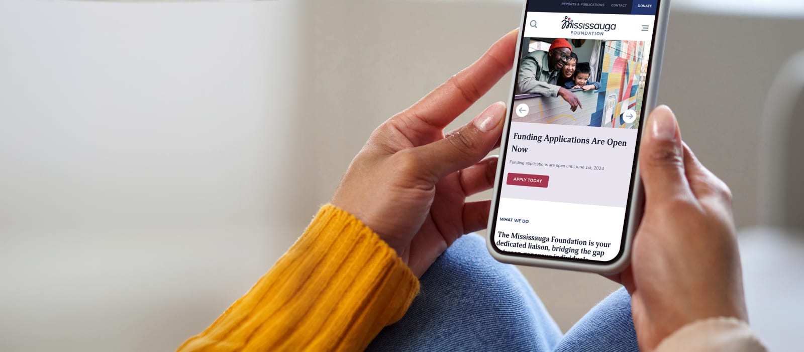 Hands hold a phone that is looking at the Mississauga Foundation website.